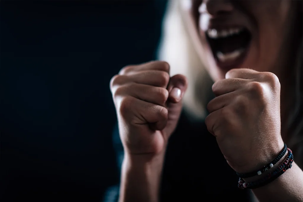 An angry woman gripping tight fists while screaming